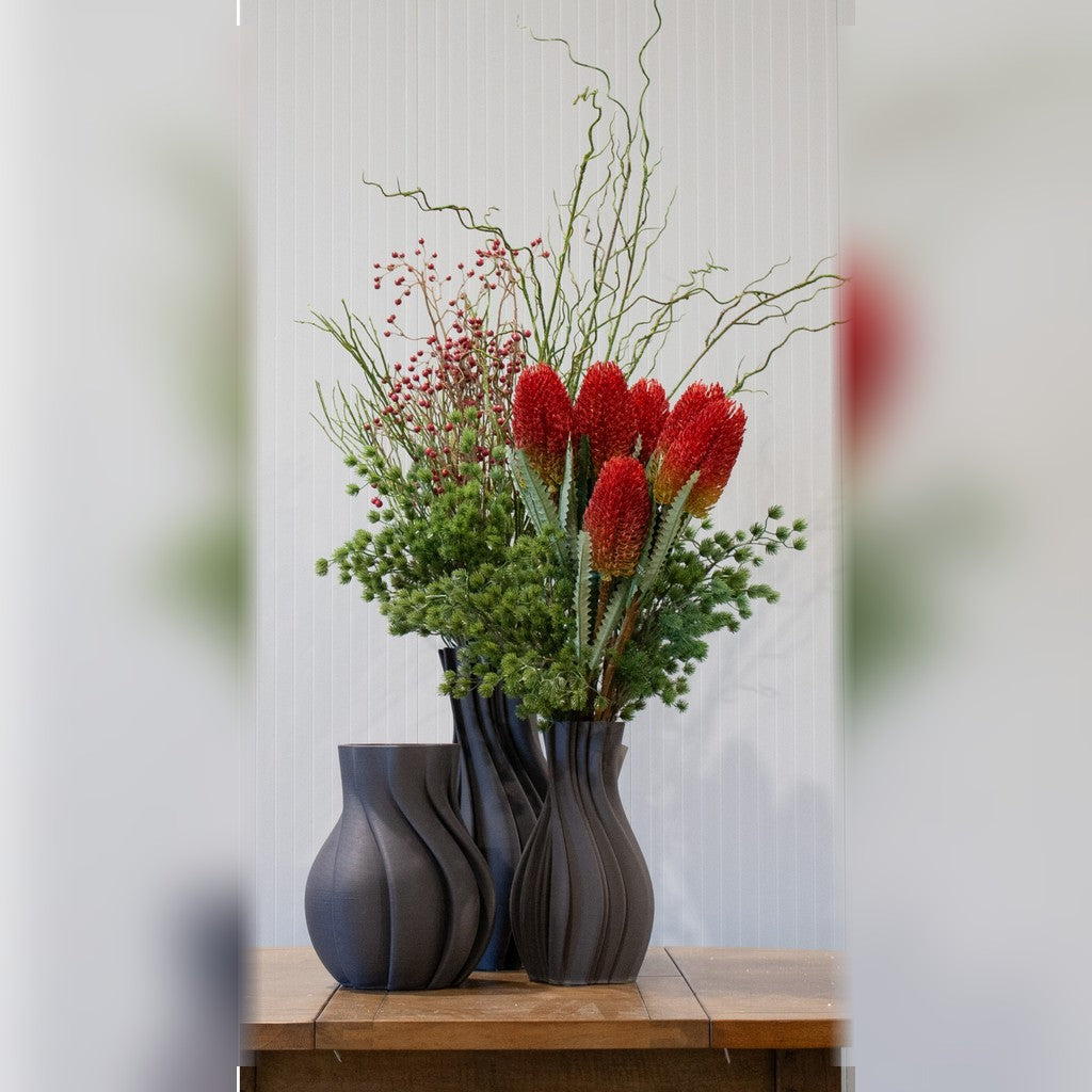 Red banksia sprays arranged with foliage in dark vases