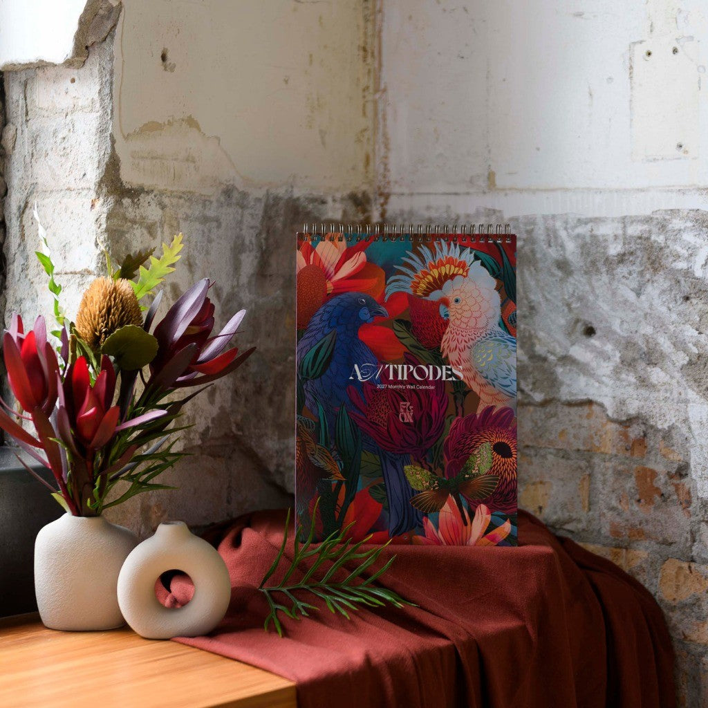FLOX Antipodes 2027 wall calendar styled on a shelf with flowers