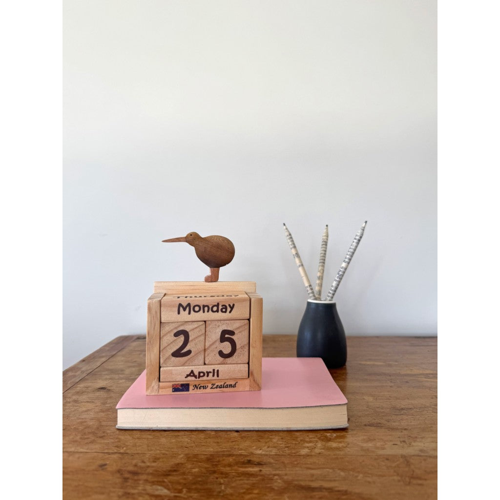 Wooden kiwi calendar on a desk with books