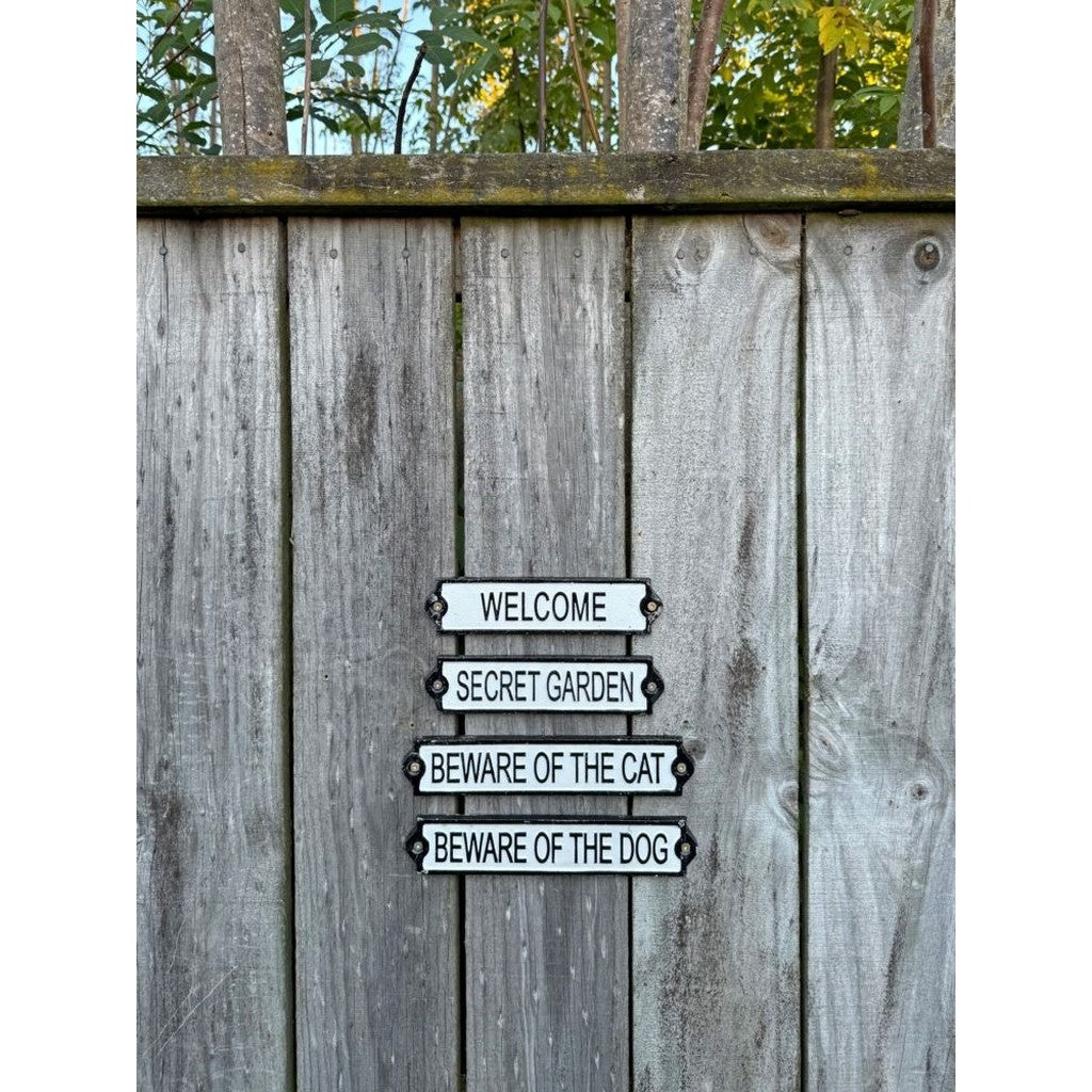 Welcome, Secret Garden and Beware of the Dog cast iron signs on a fence