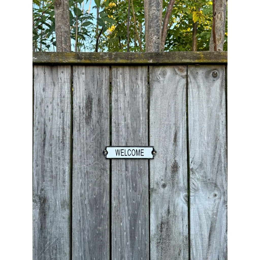 Cast iron Welcome sign fixed to a wooden fence