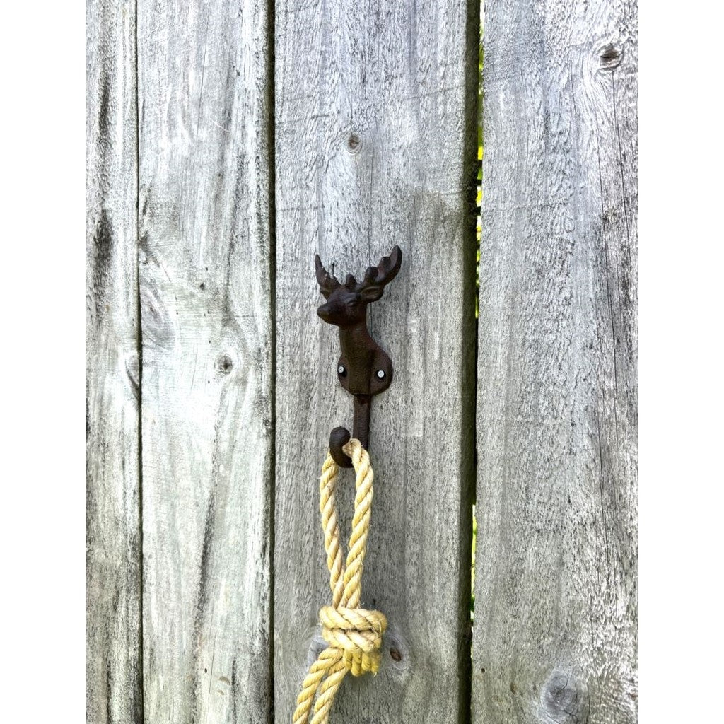 Cast iron deer wall hook on a weathered fence with rope