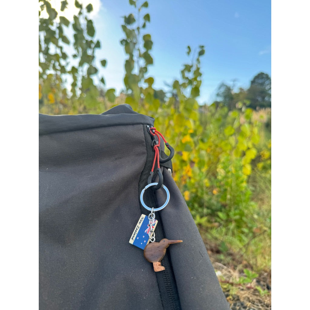 Mini wooden kiwi keyring on a bag outdoors