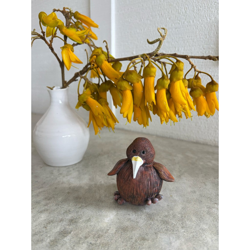 Kiwi figurine beside a vase of kōwhai flowers
