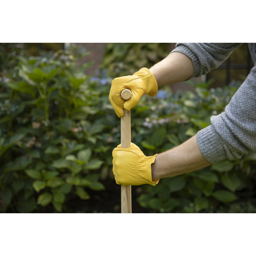 Gardener wearing yellow leather gloves holding a tool handle