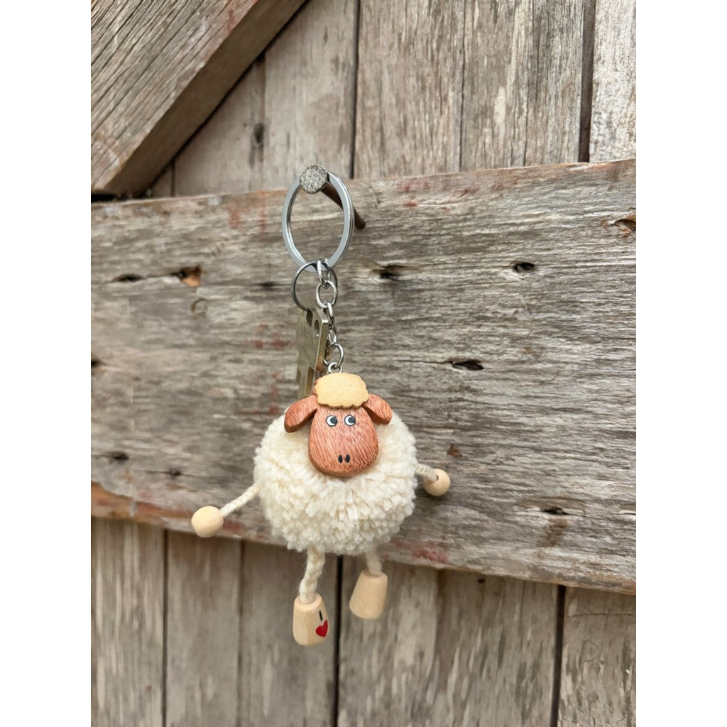 Pompom sheep keyring hanging on a weathered door